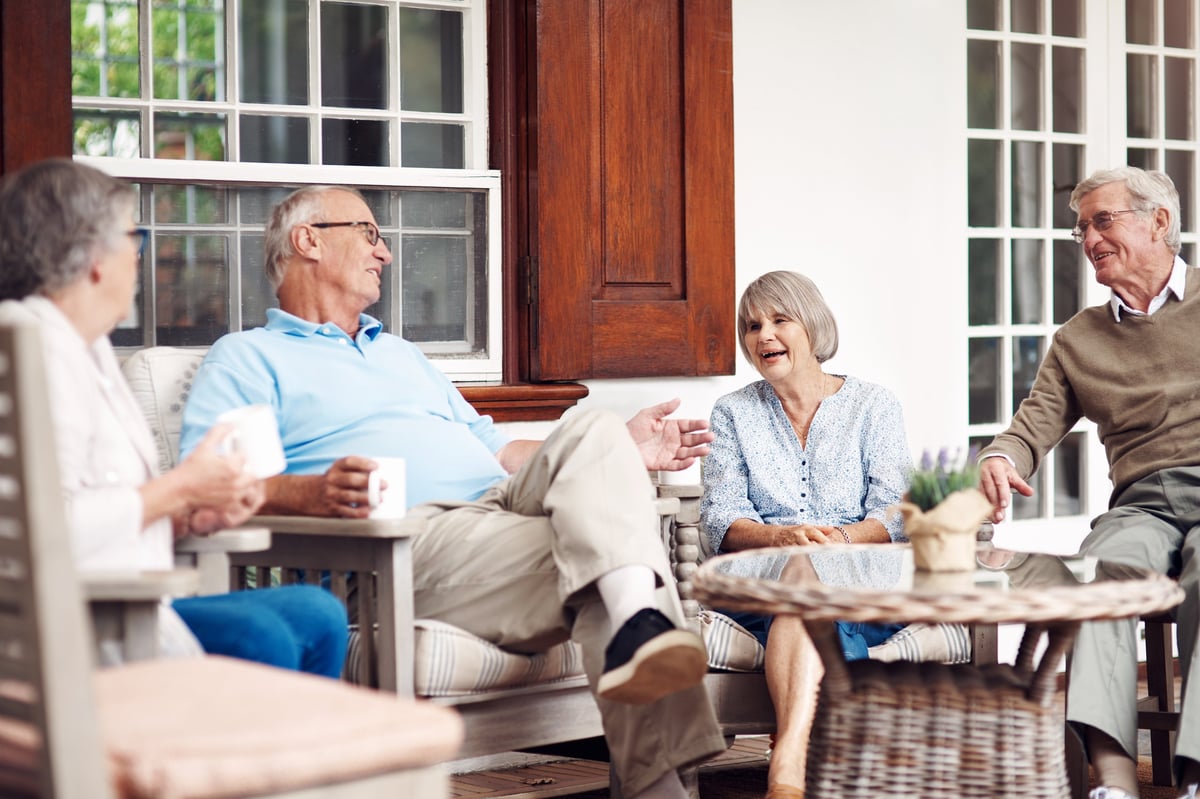 A group of older adults enjoying a sunny afternoon together on a veranda