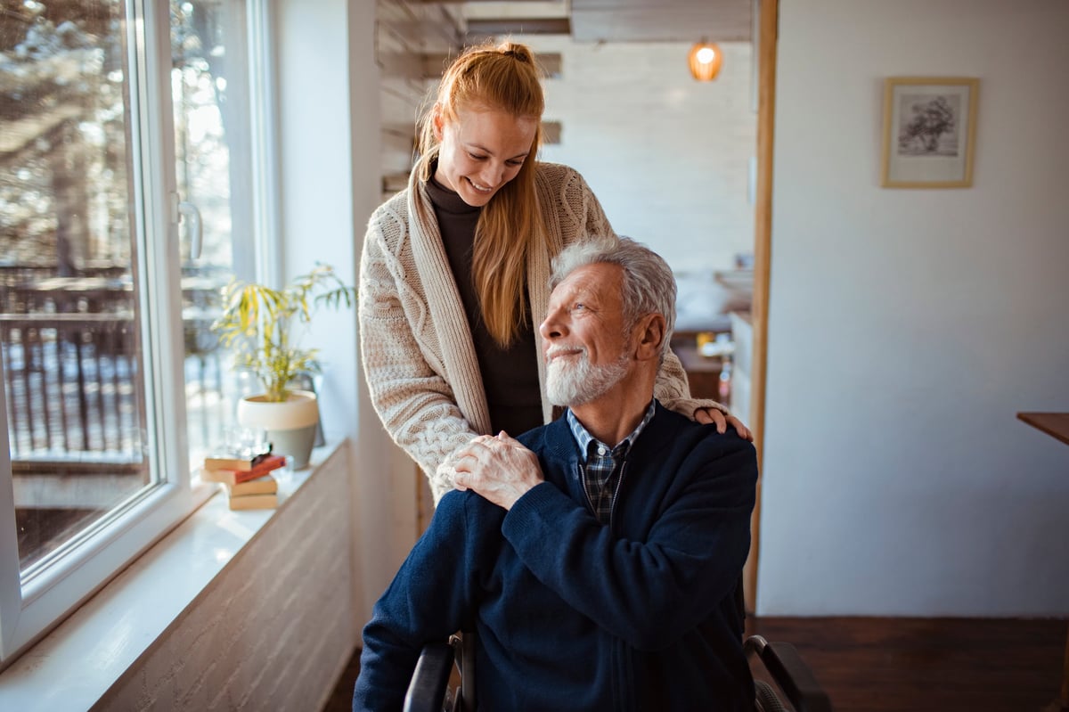 An adult daughter sitting with her father, talking together at home