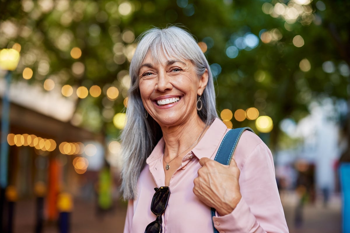 A smiling older woman looking toward the camera outdoors