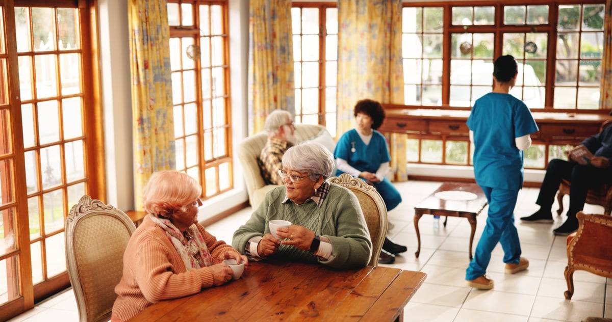Two older women enjoying coffee and conversation together in a comfortable residential community