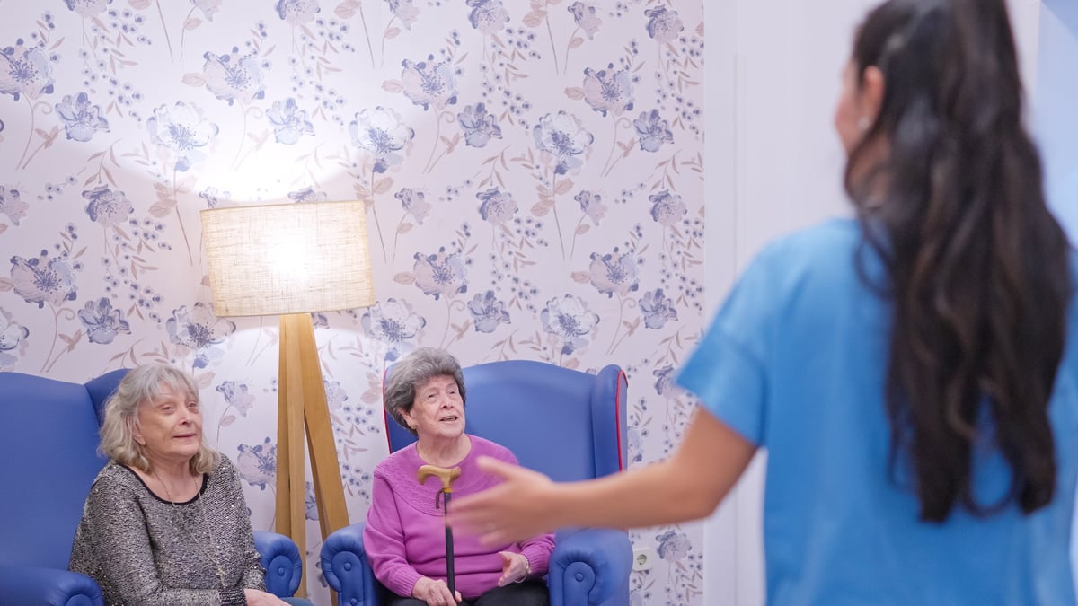 A family member greeting residents in a bright senior living community common area