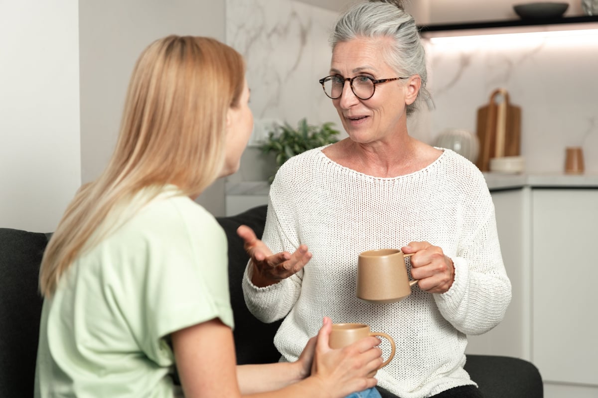 An adult daughter talking with her mother in a cozy living room